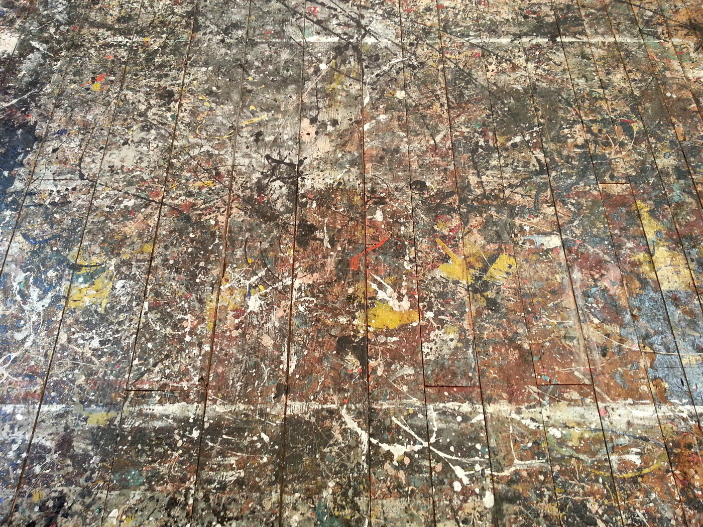 The studio floor at the Pollock-Krasner House — the first process record: every session's overflow preserved in the wood, the ancestor of the action stream and the replay. (Photo: Rhododendrites, CC BY-SA 4.0.)